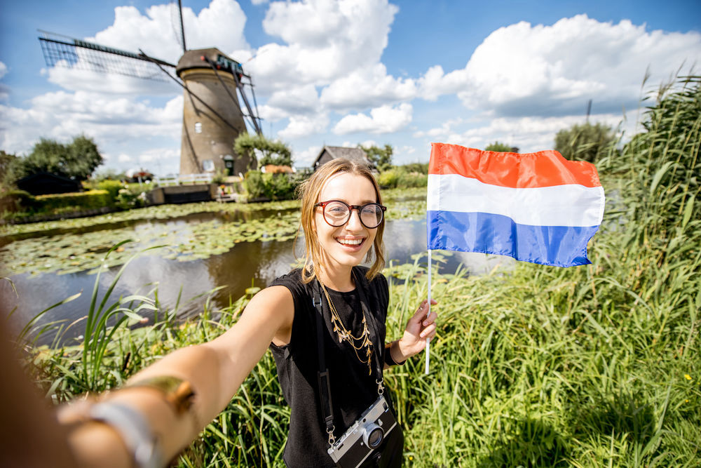 A visitor with a Dutch flag near a windmill.