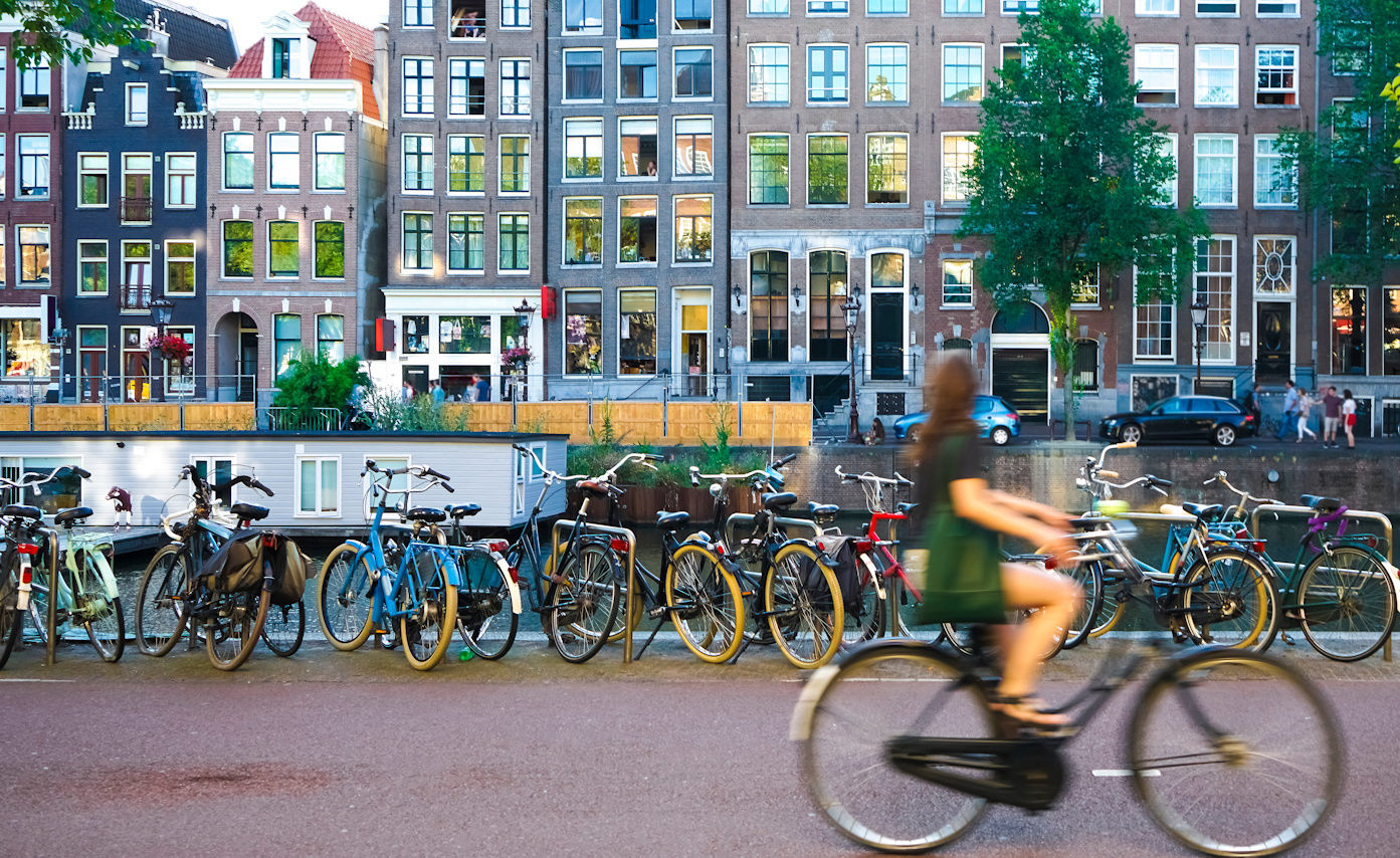 Cyclists and bicycles beside an Amsterdam canal.