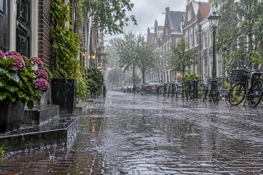 Rain falls onto a wet brick street.